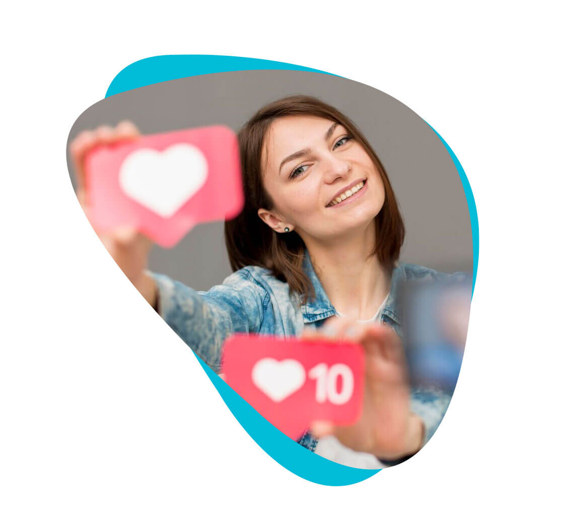A smiling woman holding two pink cards. One has a white heart. The other has a white heart and the number 10 on it.